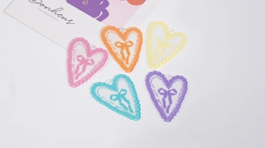 Dettaglio di ciondoli a cuore in acrilico con bordi in pizzo in cinque colori pastello per DIY