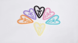 Dettaglio macro di ciondoli a cuore in acrilico con ricamo a fiocco e design colorati