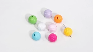 Macro shot of colorful acrylic beads with textured fish scale patterns and center holes