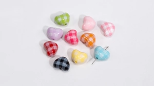 Macro shot of colorful gingham heart-shaped acrylic beads with pre-drilled holes for DIY
