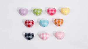 Macro shot of colorful acrylic heart beads with gingham patterns for DIY craft jewelry