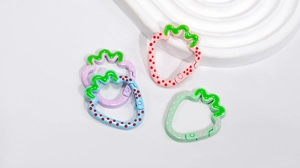 Close-up of strawberry-shaped alloy spring rings in colorful enamel for DIY keychains