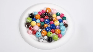 Macro-opname van kleurrijke acrylkralen met witte verfspatten in Pollock-stijl voor DIY sieraden