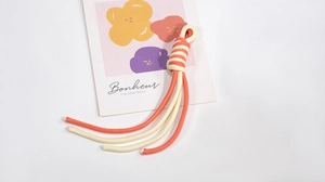 Close-up of dual-tone spiral braided lanyard in coral orange and cream white colors