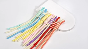 Close-up of colorful braided spiral knot wrist straps on a modern white display tray