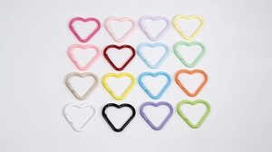 Dettaglio di 16 moschettoni a cuore in lega colorata per portachiavi e accessori borse