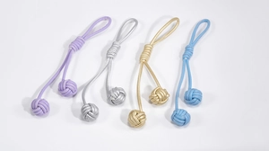 Détail de quatre porte-clés à nœuds tissés à la main en violet, doré, argenté et bleu brillant