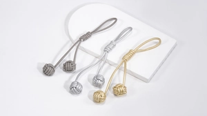 Détail de nœuds sphériques tressés à la main en finitions gris, argent et or champagne