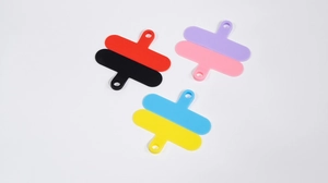 Close-up of colorful phone tether tabs in red, purple, and blue with round hanging holes