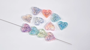 Close-up of heart-shaped iridescent acrylic beads with hammered texture for DIY jewelry making