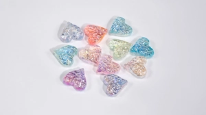 Macro detail of iridescent heart-shaped resin beads in various pastel macaron colors