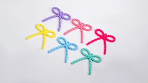 Detail view of colorful acrylic bow-shaped DIY charms with small hanging holes