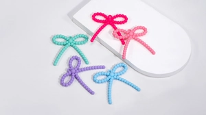 Detailed macro of candy-colored acrylic bow pendants for DIY jewelry and crafts