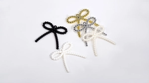 Detailed macro view of acrylic bow pendants in pearl white, black, gold and silver