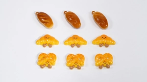 Macro detail of assorted resin cartoon bread charms including croissants and pretzels