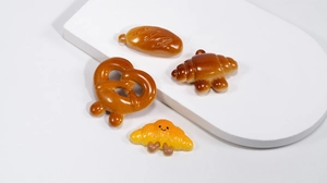 Detailed view of assorted 3D resin bread charms featuring baguette and pretzel designs