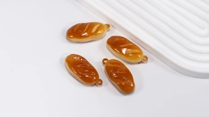 Detailed view of four realistic miniature baguette pendants with glossy finish and metal rings