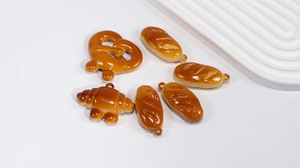 Detailed view of high-gloss resin cartoon bread charms with butterfly pretzels and croissants