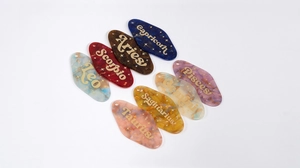 Macro view of acetate rhombus zodiac charms with glitter marble texture and gold lettering