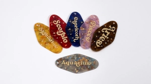Detail of glittery acrylic zodiac motel key tags in various colors with gold lettering