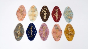Flat lay of colorful acrylic constellation motel keychains with gold glitter lettering
