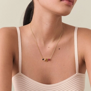 Detail view of a gold necklace on a model featuring colorful mixed gemstones