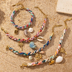 Bracelets tressés colorés avec breloques coquillages en acier doré 18 carats sur sable