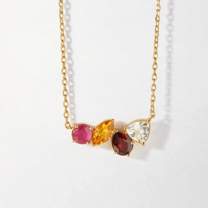 Detail of gold necklace featuring four colorful gemstones in a prong setting on white background