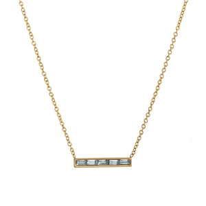 Détail macro d'un collier doré avec pendentif rectangulaire et cinq cristaux taille baguette