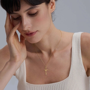 Détail d'un collier pendentif croix vintage plaqué or 18 carats porté par un mannequin