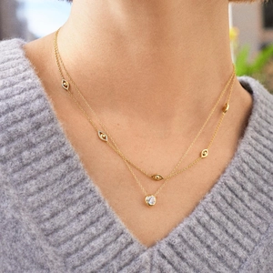 Vue détaillée d'un collier double rang doré avec pendentifs mauvais œil et cristal rond