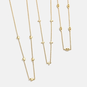 Détail de colliers en acier titane doré avec pendentifs cœur, croix et œil grec