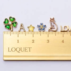 Macro detail of assorted vintage 18k gold charms including clover and stars on a scale