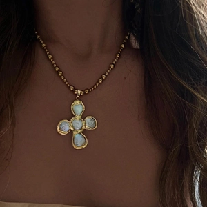 Detailed close-up of a vintage golden cross pendant necklace with iridescent pearls