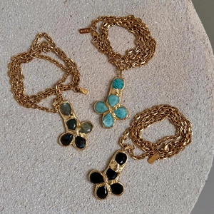 Detailed close-up of retro gold-plated necklaces with pebble-effect stone cross pendants