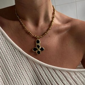 Golden beaded necklace with vintage cross pendant featuring five black oval stones