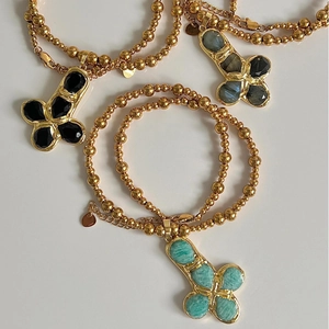 Detailed view of bohemian gold beaded necklaces with colorful stone cross pendants