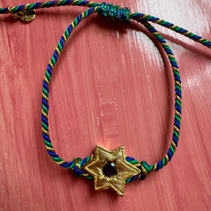 Macro view of woven cord bracelet with gold star pendant and purple gemstone detail