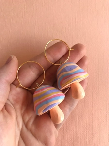 Detail of handmade colorful clay mushroom hoop earrings held in hand for size reference
