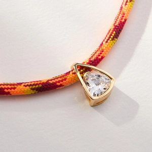Detailed close-up of a triangular zircon pendant with a colorful braided cord necklace