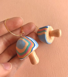 Macro detail of handmade colorful striped mushroom earrings with golden metal hooks
