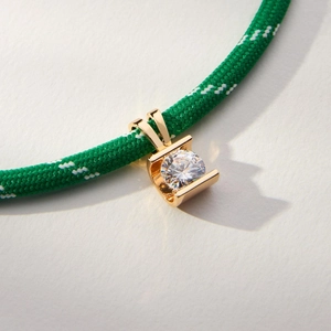 Macro detail of a clear round zircon pendant on a vibrant green braided cord necklace