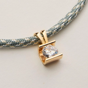 Macro detail of gold-plated circular zircon pendant with multicolor braided cord