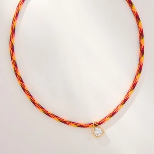 Detail of colorful woven cord necklace with a gold triangle pendant and zircon stone