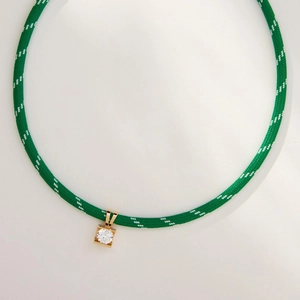 Close-up of woven green and white cord necklace with a gold zircon square pendant