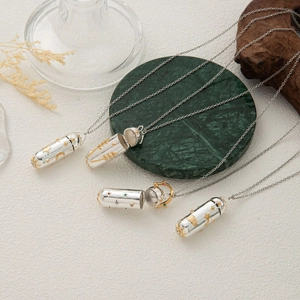 Detalle de collar relicario con diseño de cápsula vintage y motivos de luna, estrella y gemas