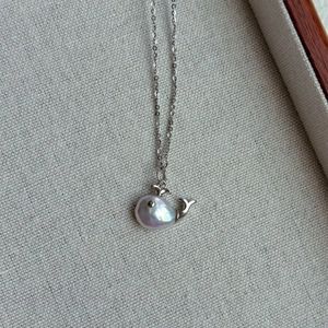 Macro view of whale pendant with baroque pearl and silver metal fin details