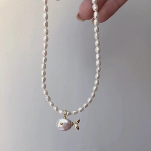 Macro detail of whale pendant with baroque pearl and golden fins on a pearl necklace