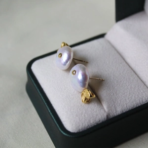 Close-up of lavender baroque pearl earrings with golden accents on luxury jewelry box