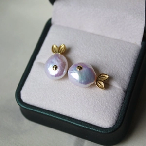 Macro shot of baroque pearl whale earrings with golden fins in a premium gift box